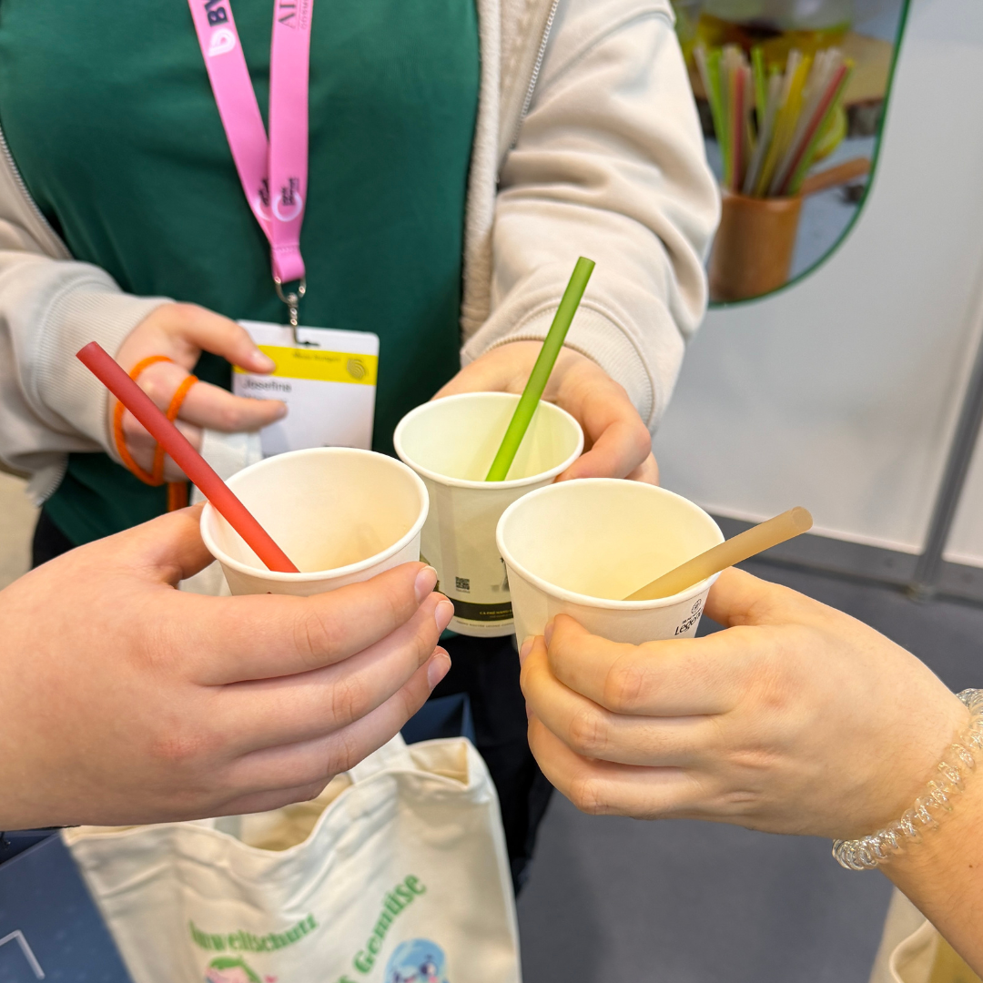 Hände mit Bechern und Strohhalmen